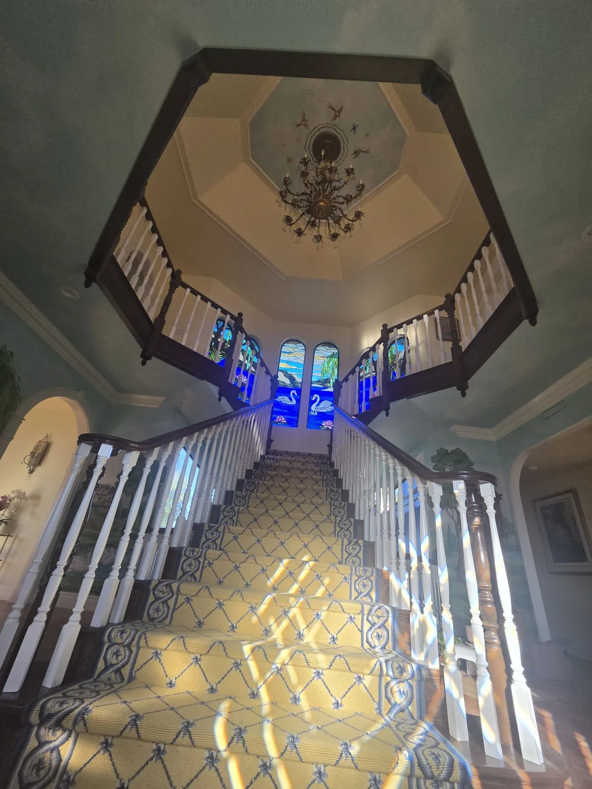 Grand staircase foyer with a hand-painted sky mural on the domed ceiling.