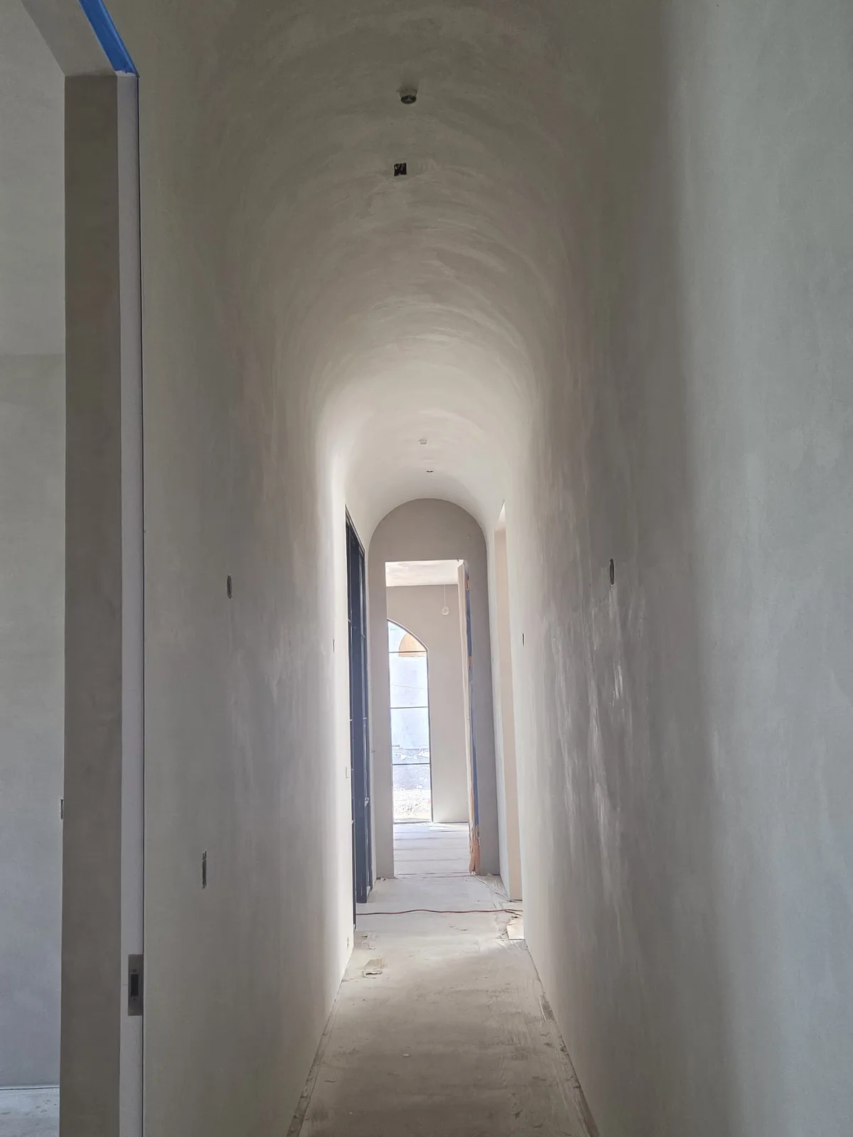 Vaulted, hand-troweled Venetian plaster corridor with an arched doorway.